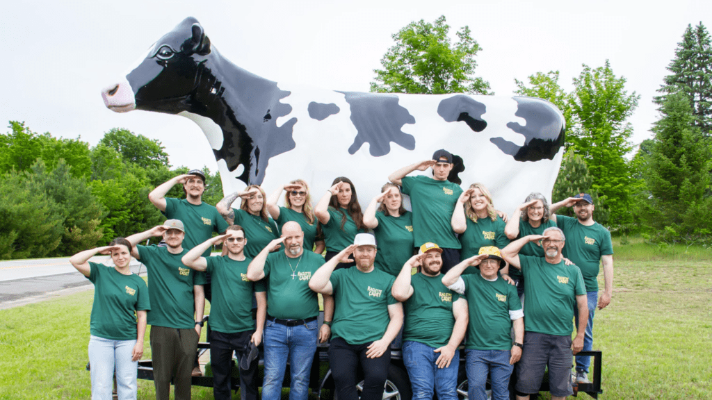 Members of the Leelanau Cheese Company's Raclette Cadets standing in front of an enormous cow statue at Cheese Fest