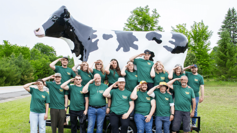Members of the Leelanau Cheese Company's Raclette Cadets standing in front of an enormous cow statue at Cheese Fest