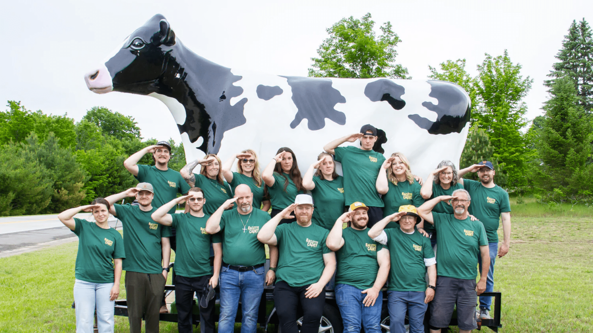 Members of the Leelanau Cheese Company's Raclette Cadets standing in front of an enormous cow statue at Cheese Fest